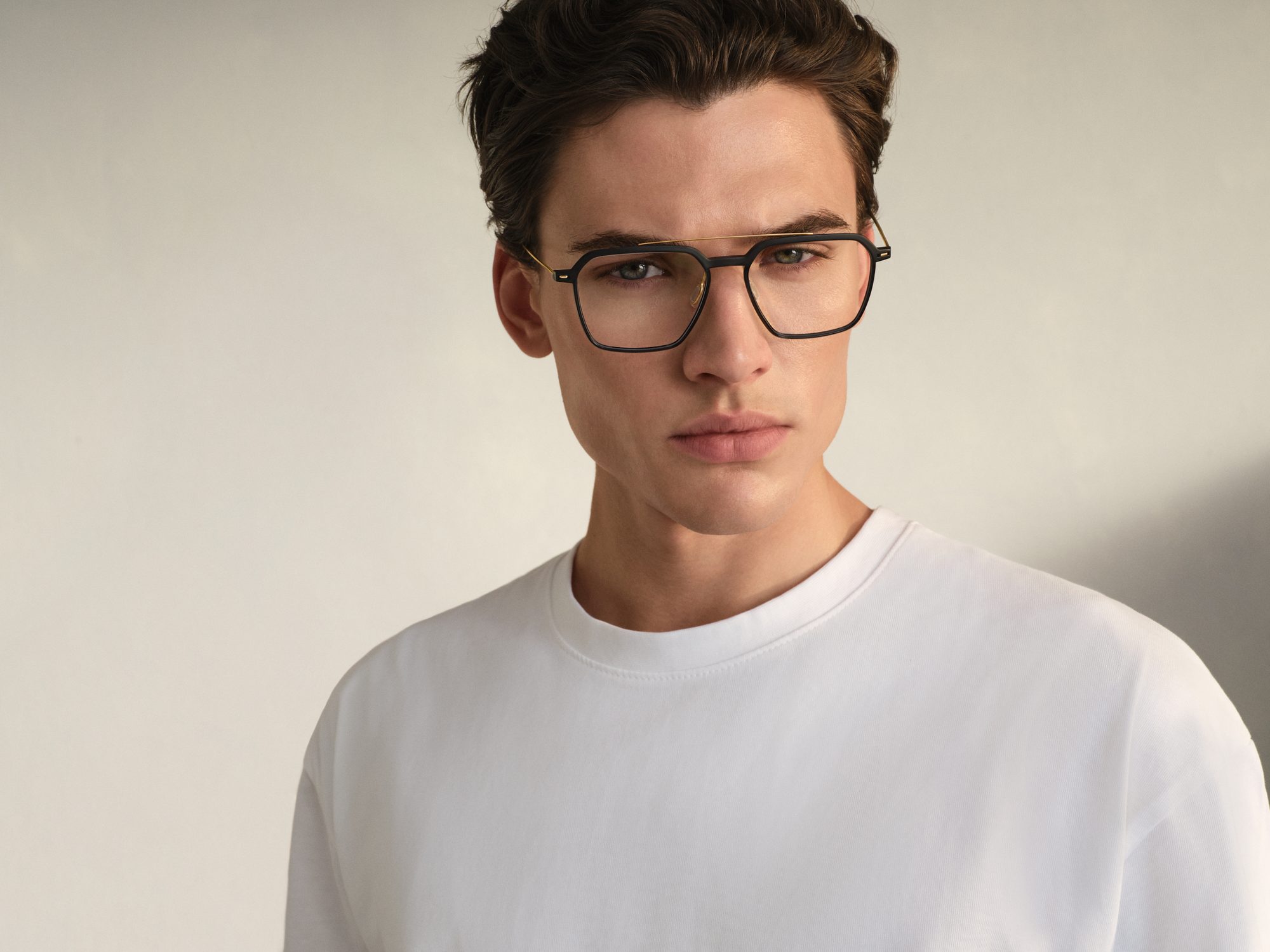 Portrait of a man in a white T-shirt wearing black Rodenstock double-bridge eyeglasses