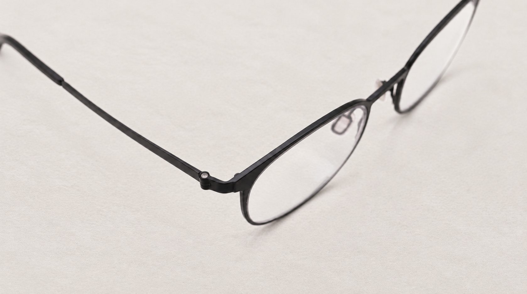 Loop key visual: close-up of a dark Loop frame and its hinge on light stone